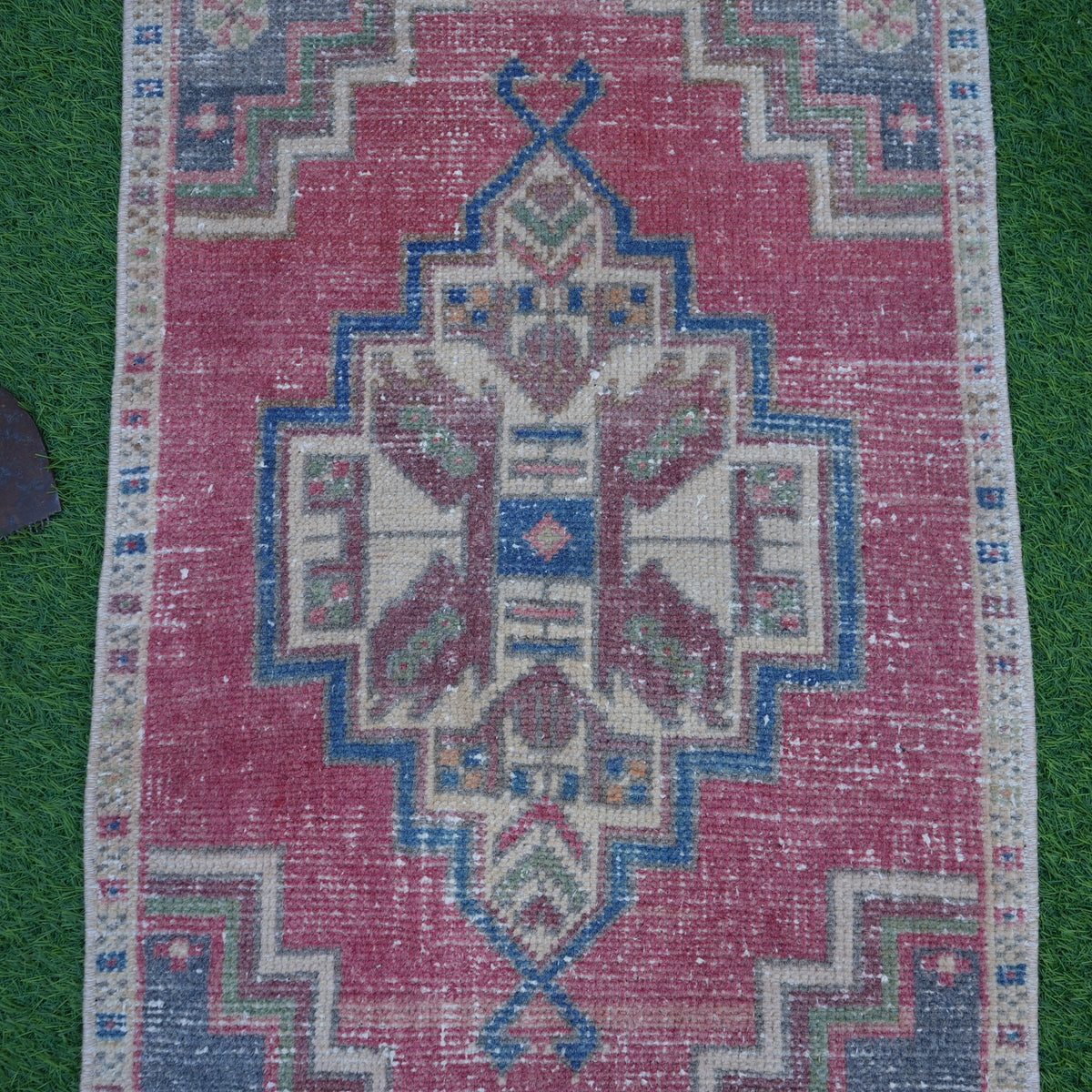 Close-up of the red vintage turkish rug showing traditional details, hand-knotted weave, wool and cotton and low pile.