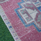 Red 1' x 3' vintage turkish rug in wool and cotton, shown on the floor.