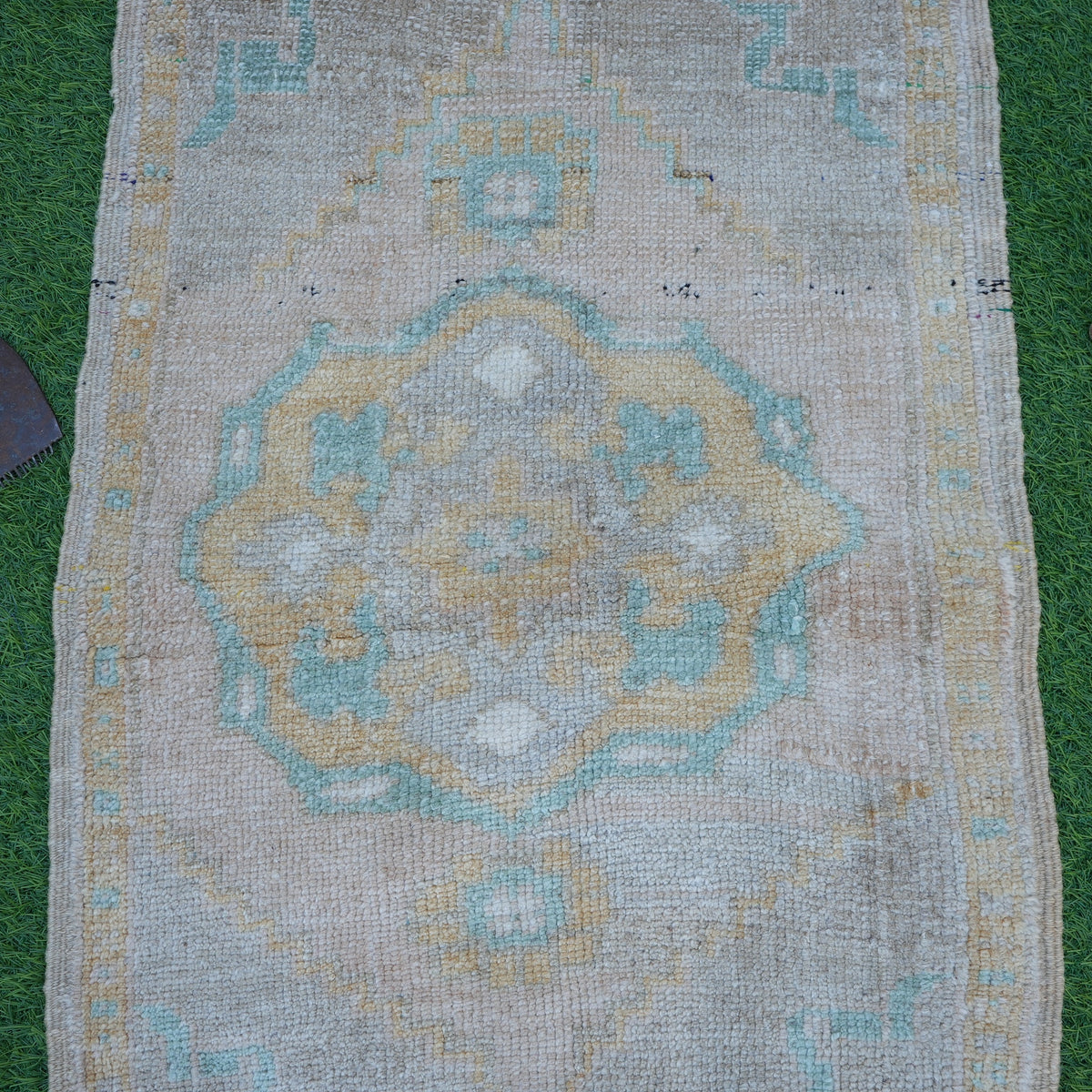 Close-up of the beige vintage turkish rug showing neutral details, hand-knotted weave, wool and cotton and low pile.