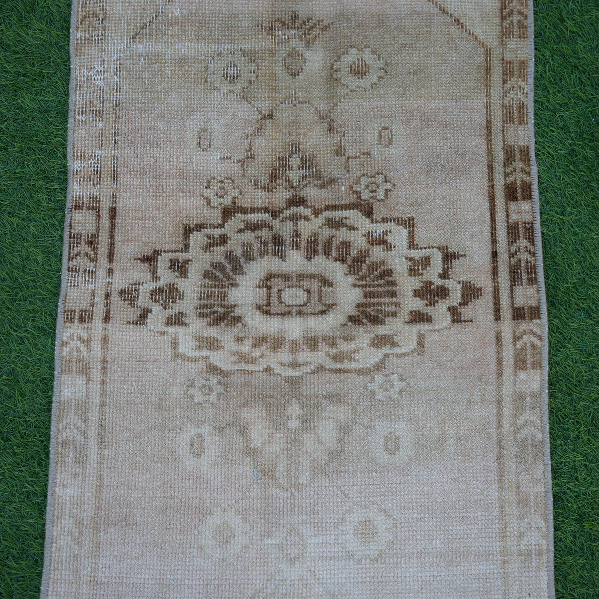 Close-up of the beige vintage turkish rug showing neutral details, hand-knotted weave, wool and cotton and low pile.