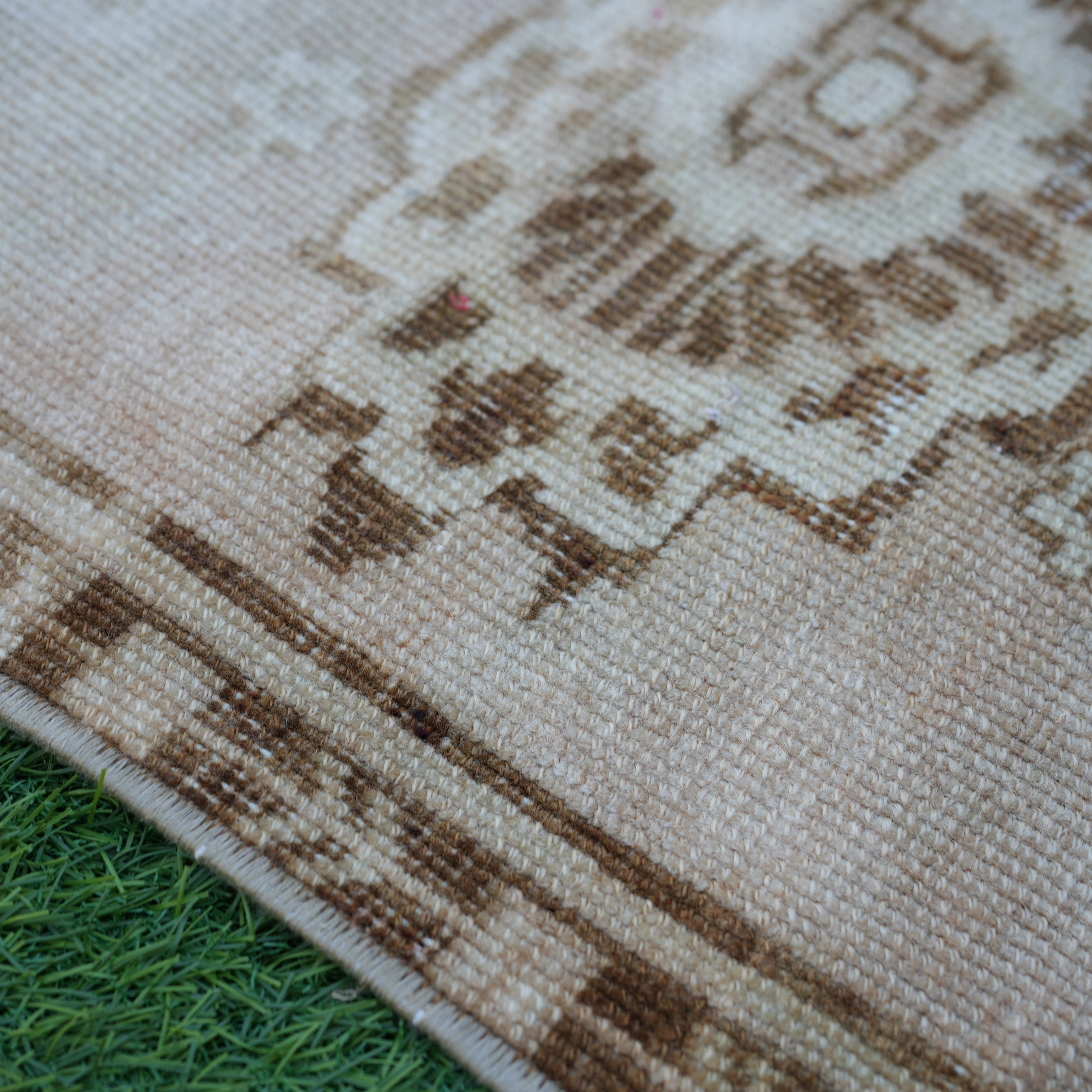 Beige 2' x 3' vintage turkish rug in wool and cotton, shown on the floor.