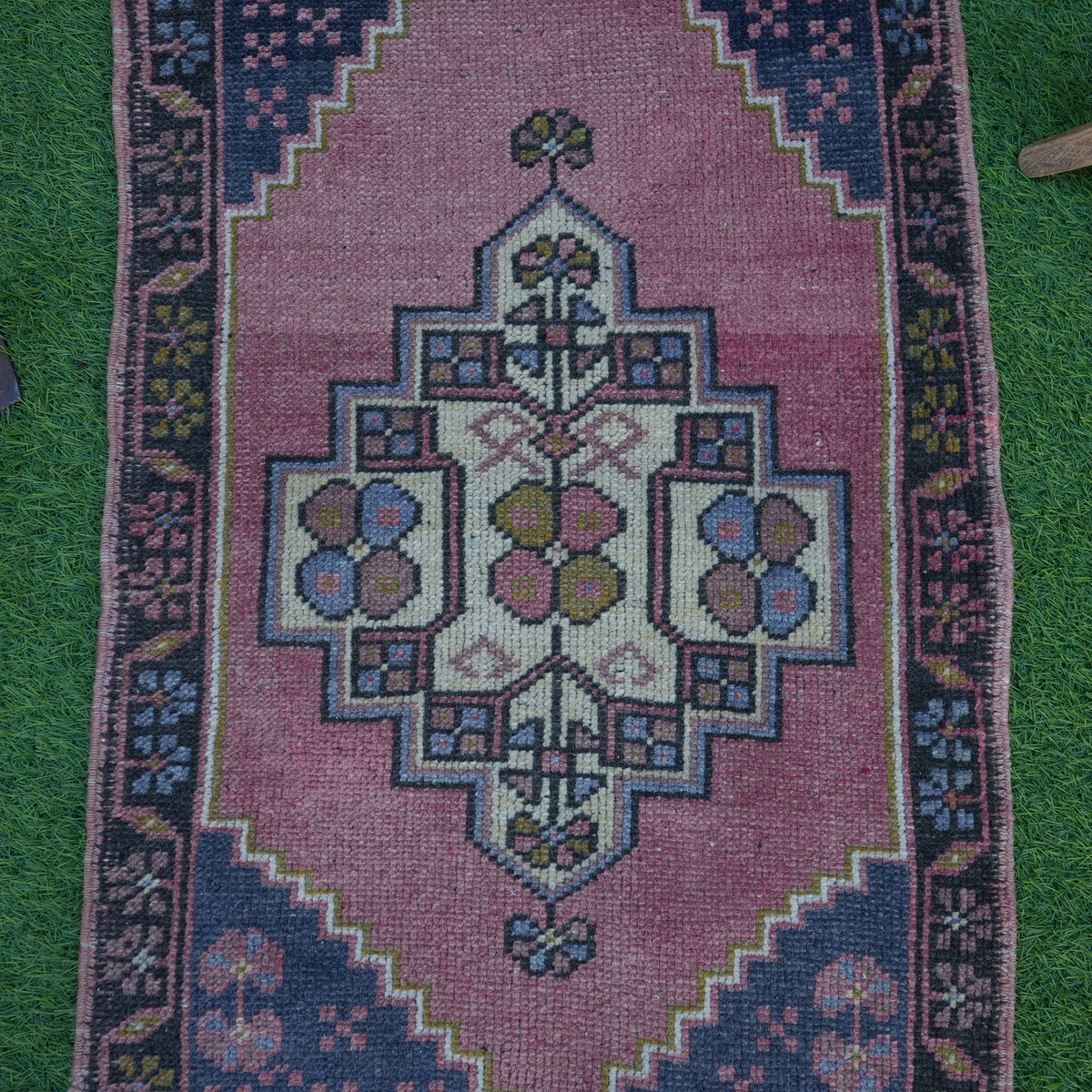 Close-up of the pink vintage turkish rug showing traditional details, hand-knotted weave, wool and cotton and low pile.