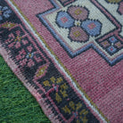 Pink 2' x 3' vintage turkish rug in wool and cotton, shown on the floor.