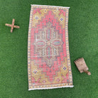 Pink 2' x 3' vintage turkish rug in wool and cotton, shown on the floor.