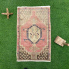Pink 2' x 3' vintage turkish rug in wool and cotton, shown on the floor.