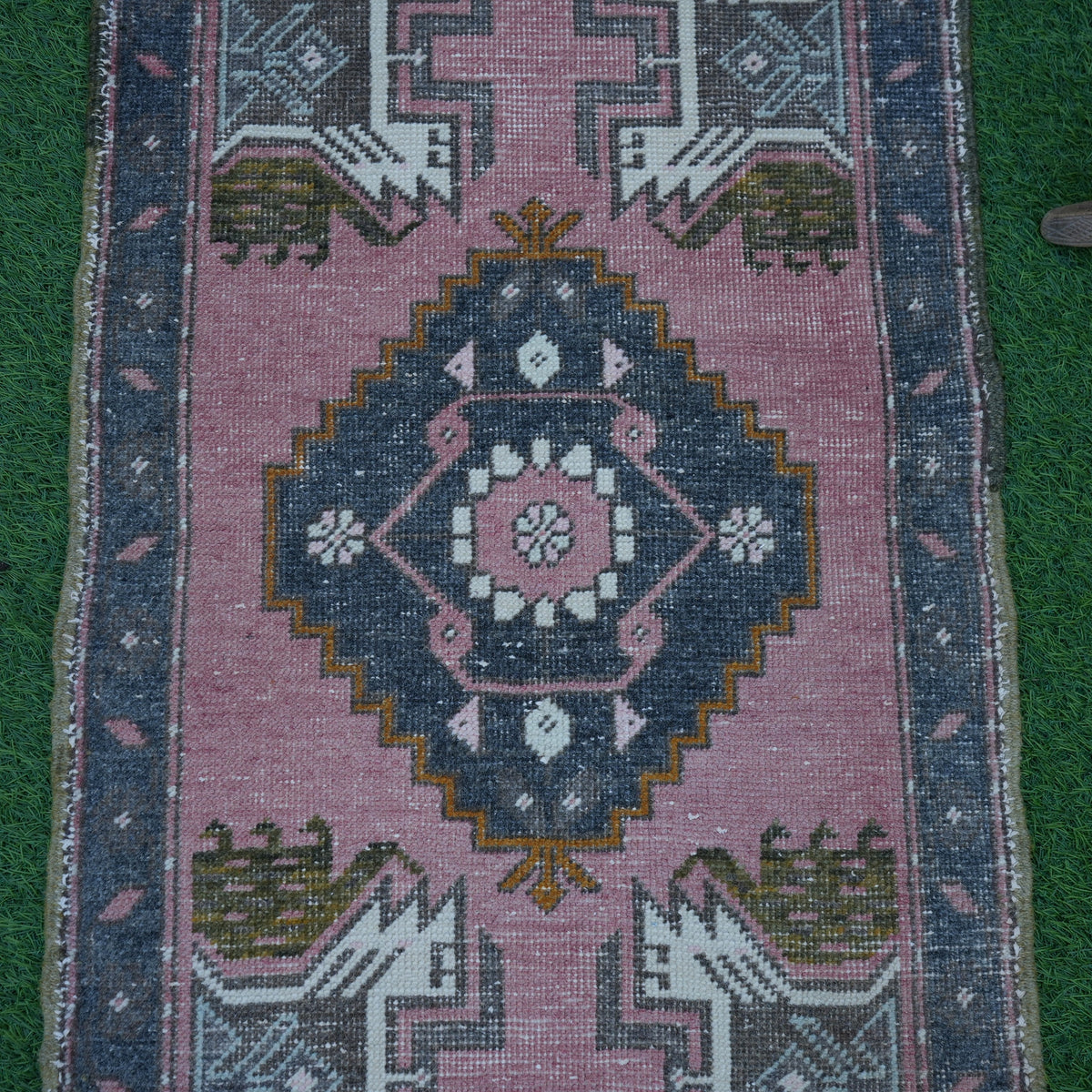 Close-up of the pink vintage turkish rug showing traditional details, hand-knotted weave, wool and cotton and low pile.