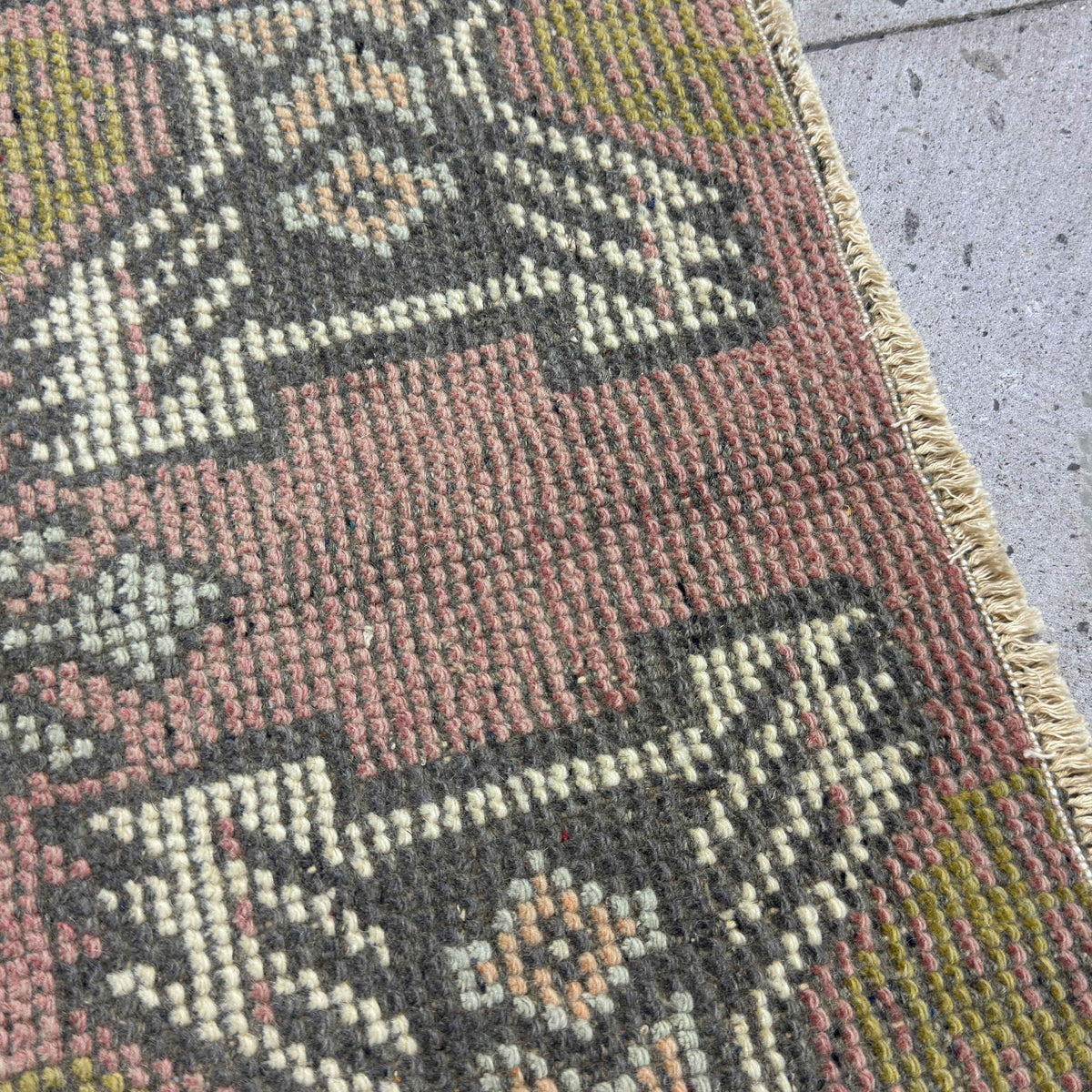 Close-up of the pink vintage turkish rug showing traditional details, hand-knotted weave, wool and cotton and low pile.