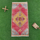 Red 2' x 3' vintage turkish rug in wool and cotton, shown on the floor.