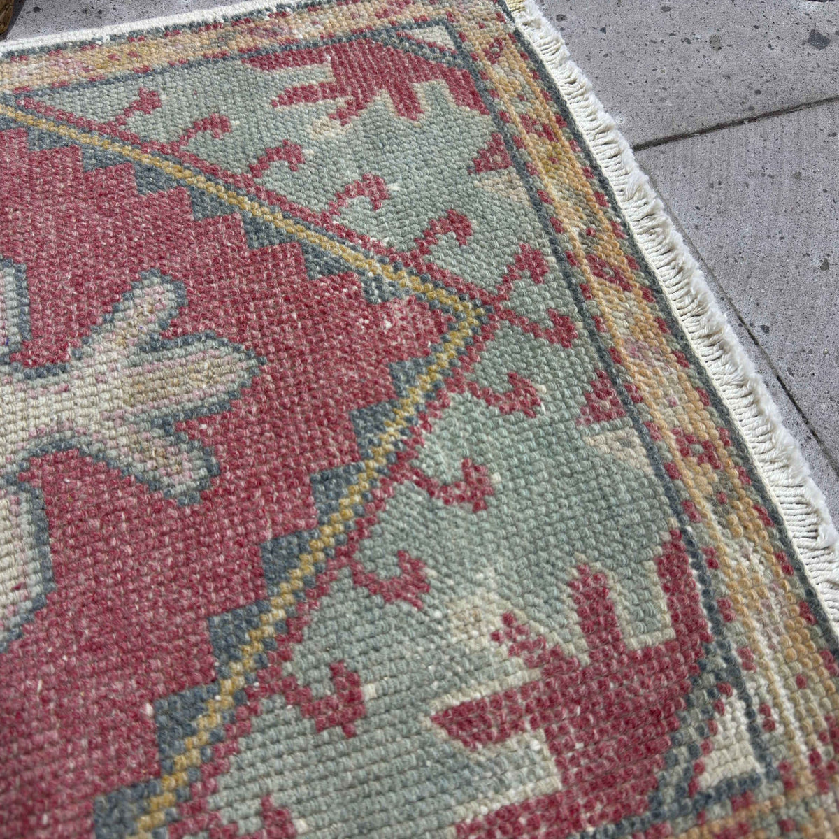 Close-up of the red vintage turkish rug showing traditional details, hand-knotted weave, wool and cotton and low pile.