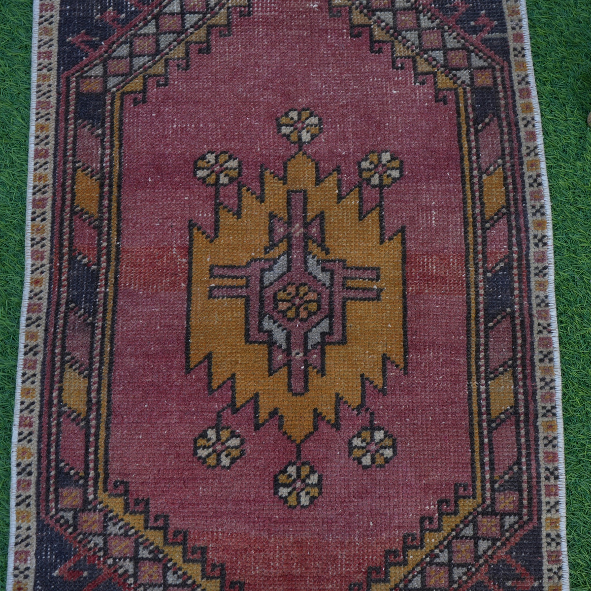 Close-up of the red vintage turkish rug showing traditional details, hand-knotted weave, wool and cotton and low pile.