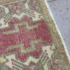 Close-up of the red vintage turkish rug showing medallion details, hand-knotted weave, wool and cotton and low pile.