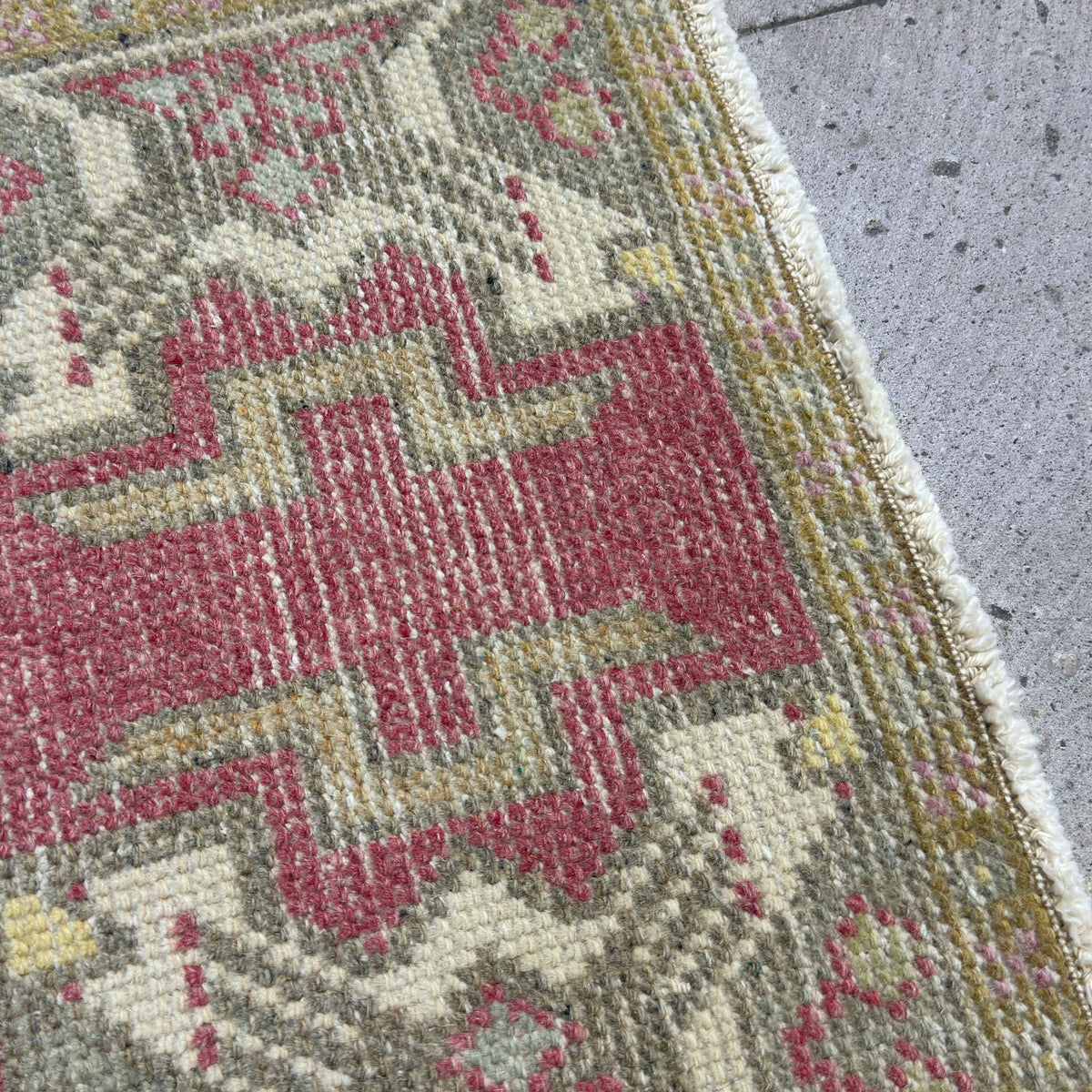 Close-up of the red vintage turkish rug showing medallion details, hand-knotted weave, wool and cotton and low pile.