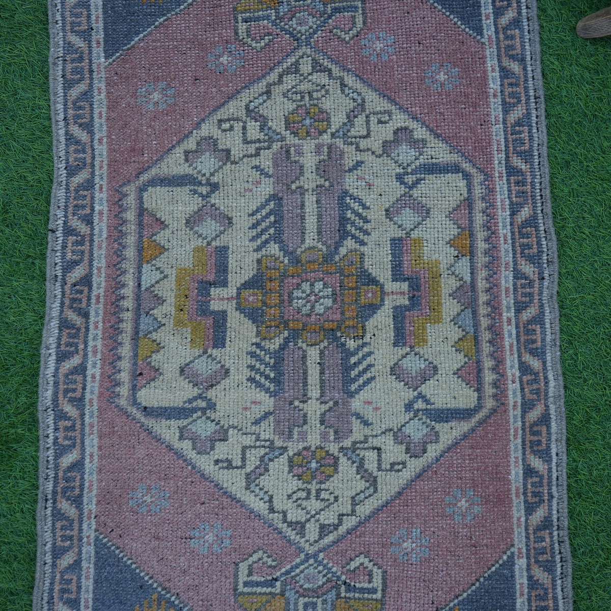 Close-up of the pink vintage turkish rug showing traditional details, hand-knotted weave, wool and cotton and low pile.
