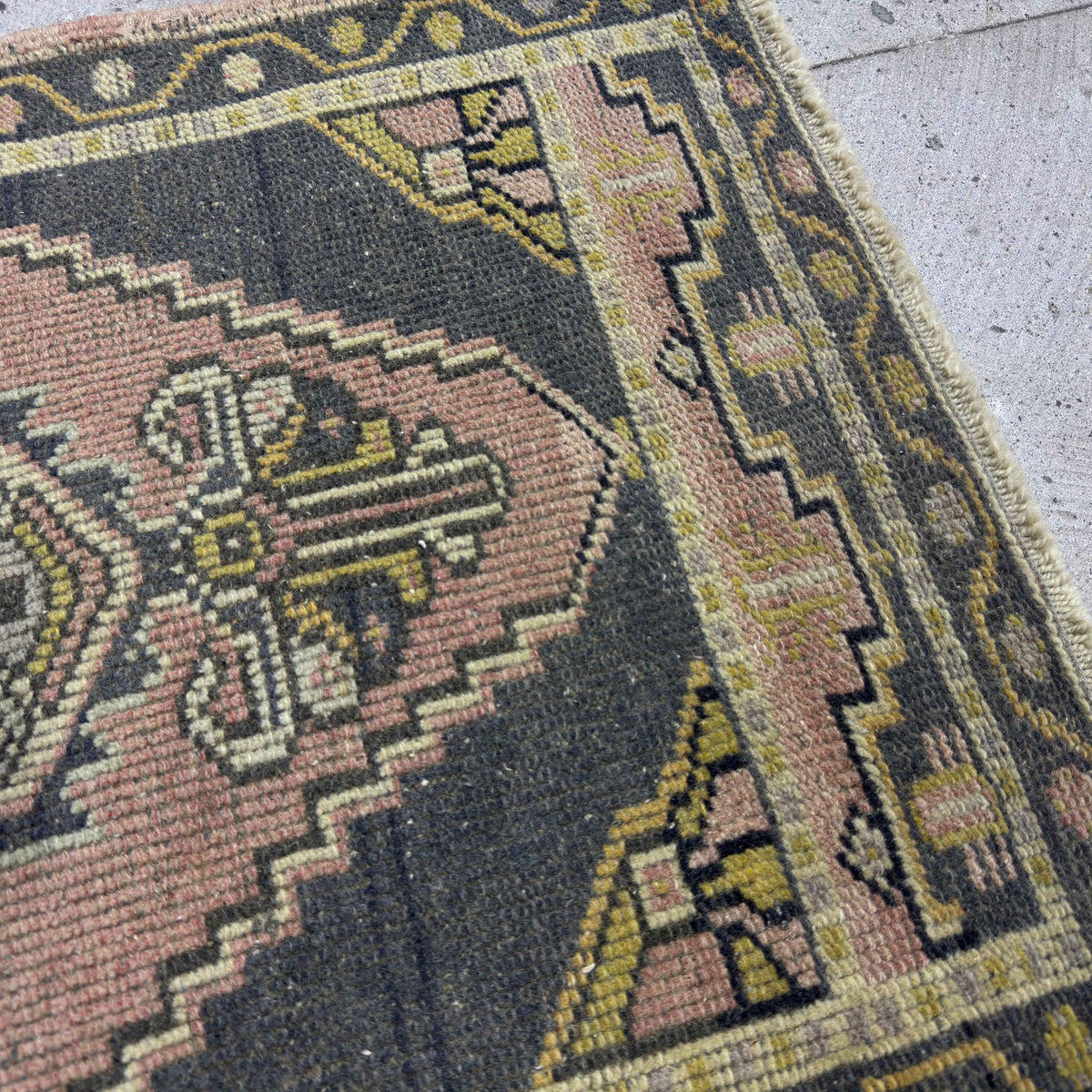 Close-up of the pink vintage turkish rug showing traditional details, hand-knotted weave, wool and cotton and low pile.