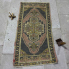 Pink 2' x 4' vintage turkish rug in wool and cotton, shown on the floor.