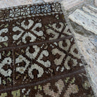 Close-up of the brown vintage turkish rug showing patchwork details, hand-knotted weave, wool and cotton and low pile.