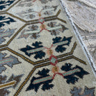 Close-up of the beige vintage turkish rug showing floral details, hand-knotted weave, wool and cotton and low pile.