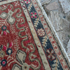 Close-up of the red vintage turkish rug showing geometric details, hand-knotted weave, wool and cotton and low pile.