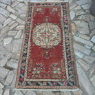 Red 3' x 6' vintage turkish rug in wool and cotton, shown on the floor.