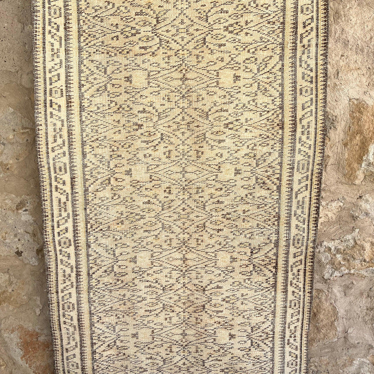 Beige 3' x 7' vintage turkish rug in wool and cotton, shown on the floor.