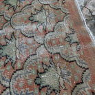 Close-up of the pale orange vintage turkish rug showing geometric details, hand-knotted weave, wool and cotton and low pile.