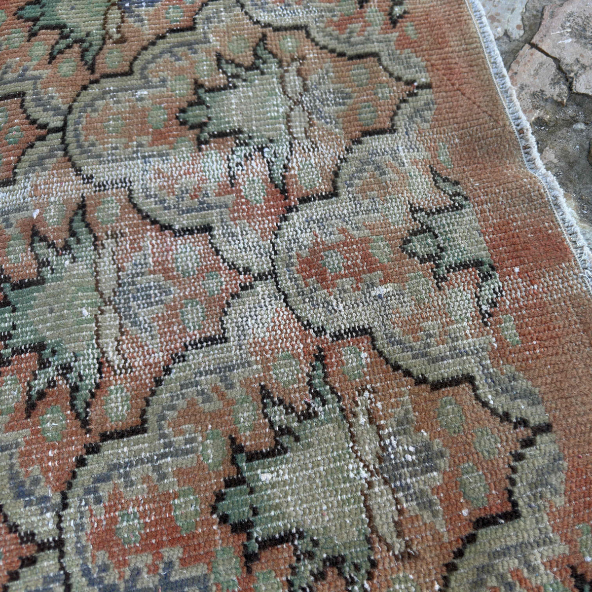 Close-up of the pale orange vintage turkish rug showing geometric details, hand-knotted weave, wool and cotton and low pile.
