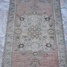 Close-up of the pale red vintage turkish rug showing medallion details, hand-knotted weave, wool and cotton and low pile.