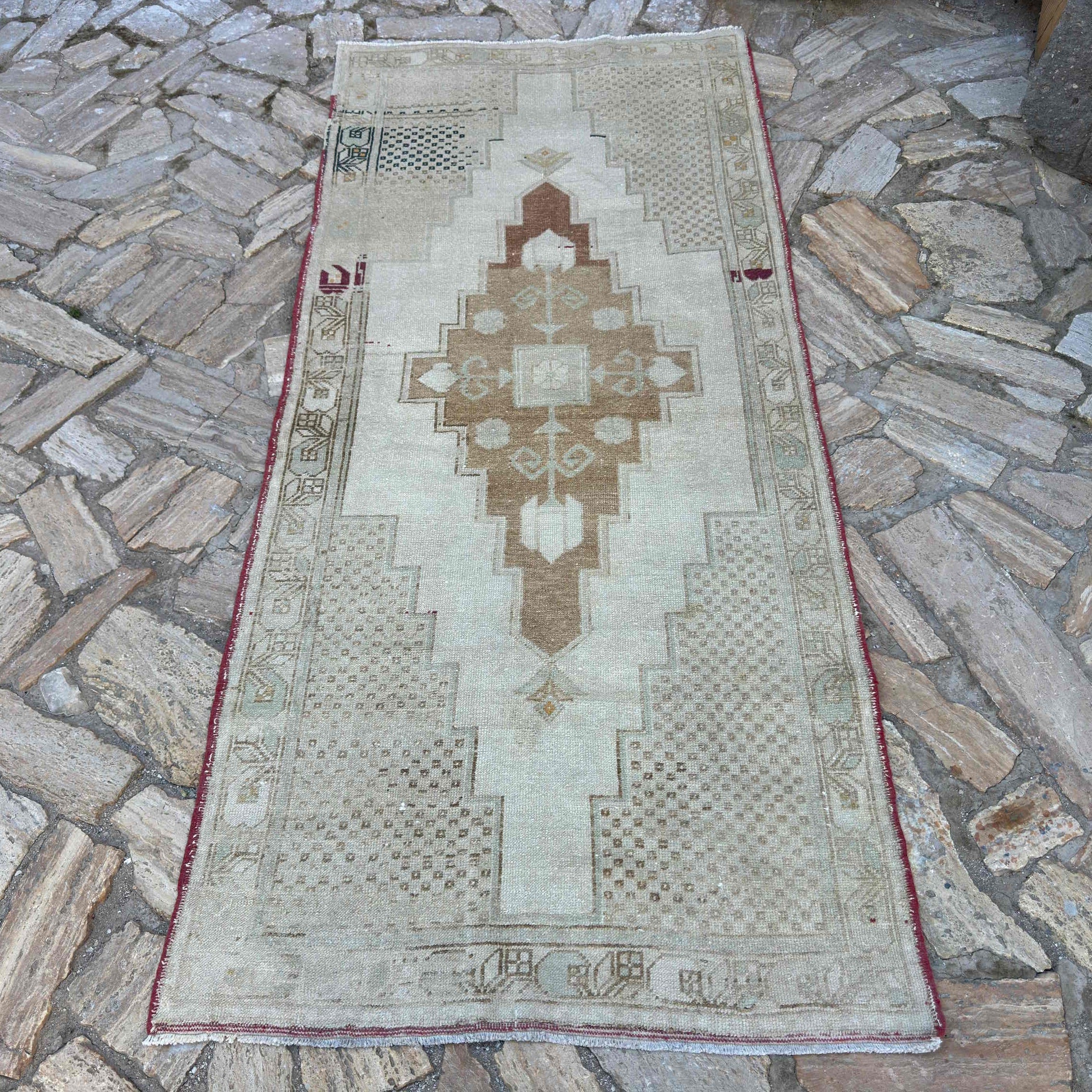 Brown 3' x 8' vintage turkish rug in wool and cotton, shown on the floor.