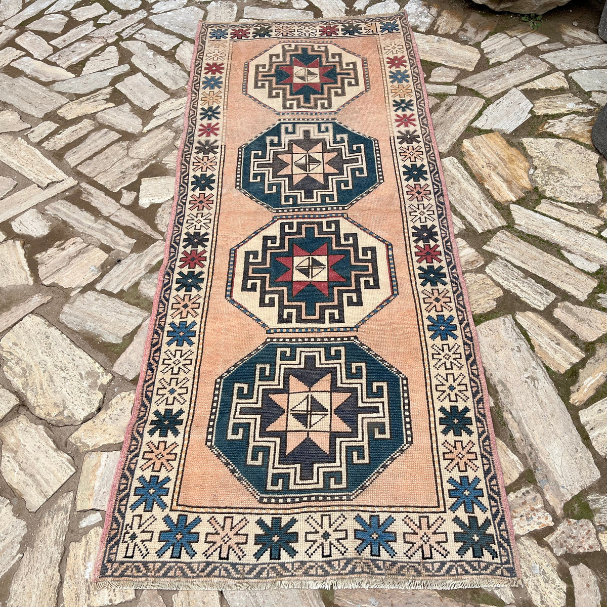 Pink 3' x 8' vintage turkish rug in wool and cotton, shown on the floor.