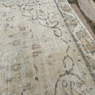Close-up of the beige vintage turkish rug showing medallion details, hand-knotted weave, wool and cotton and low pile.