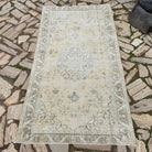 Beige 4' x 7' vintage turkish rug in wool and cotton, shown on the floor.
