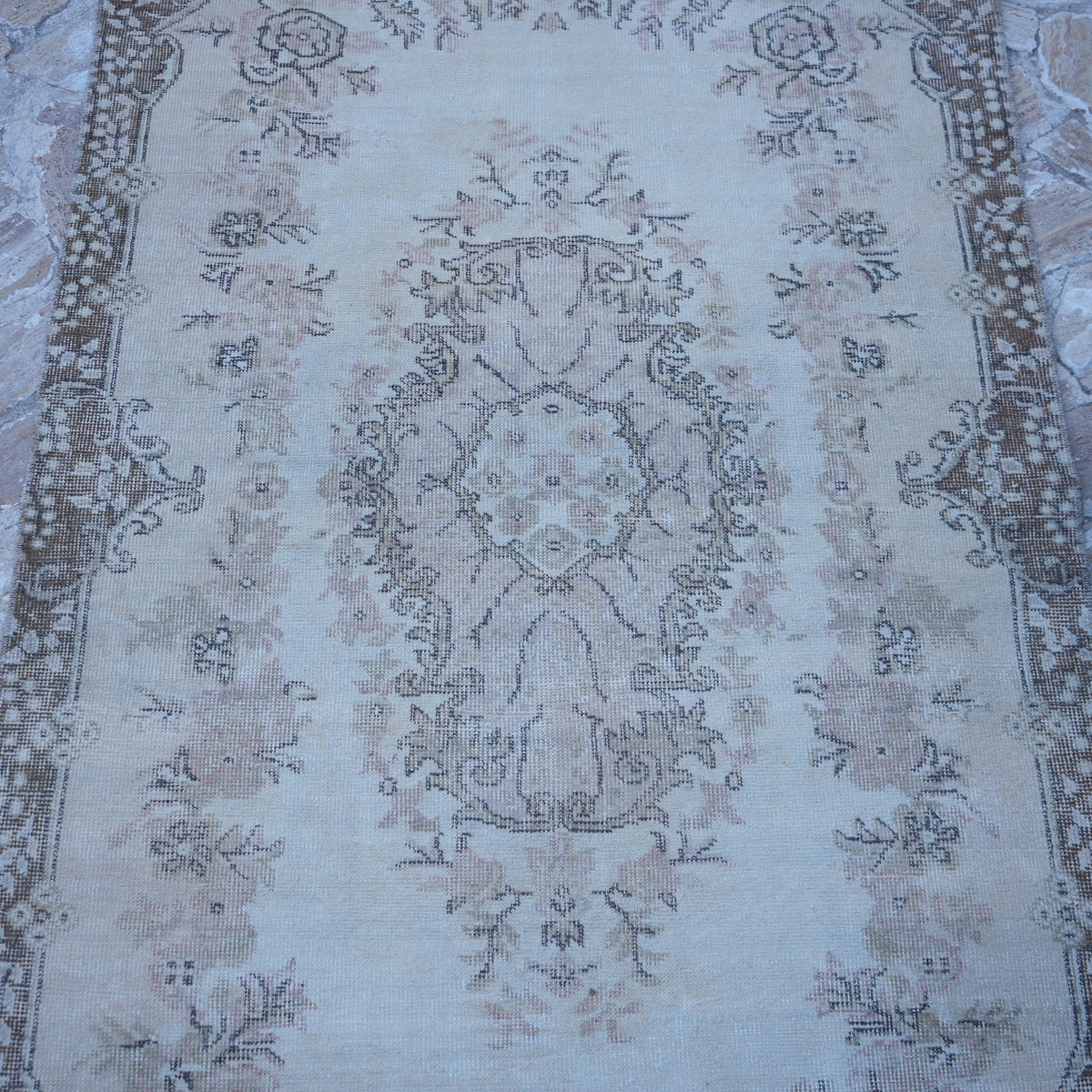 Close-up of the beige vintage turkish rug showing traditional details, hand-knotted weave, wool and cotton and low pile.