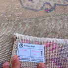 Close-up of the beige vintage turkish rug showing medallion details, hand-knotted weave, wool and cotton and low pile.
