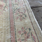 Close-up of the beige vintage turkish rug showing neutral details, hand-knotted weave, wool and cotton and low pile.