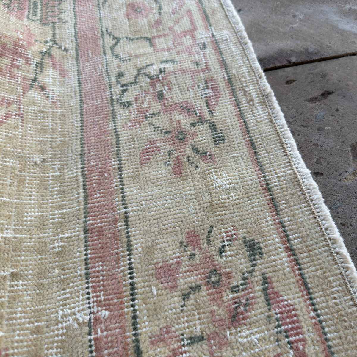 Close-up of the beige vintage turkish rug showing neutral details, hand-knotted weave, wool and cotton and low pile.