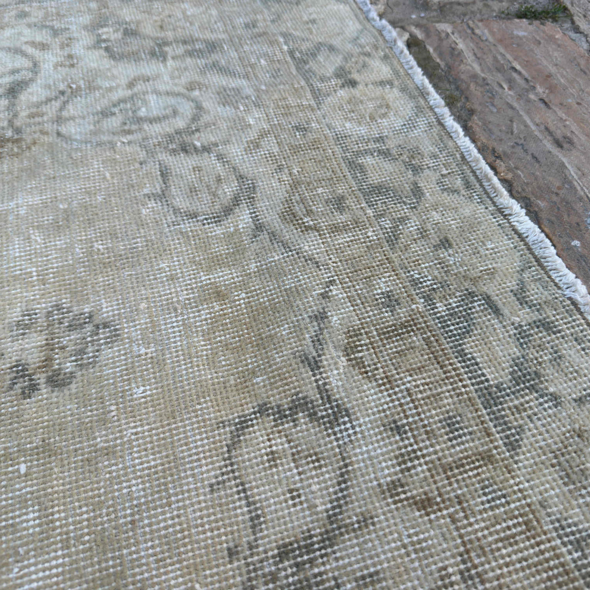 Close-up of the beige vintage turkish rug showing neutral details, hand-knotted weave, wool and cotton and low pile.