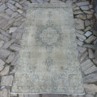 Beige 4' x 7' vintage turkish rug in wool and cotton, shown on the floor.