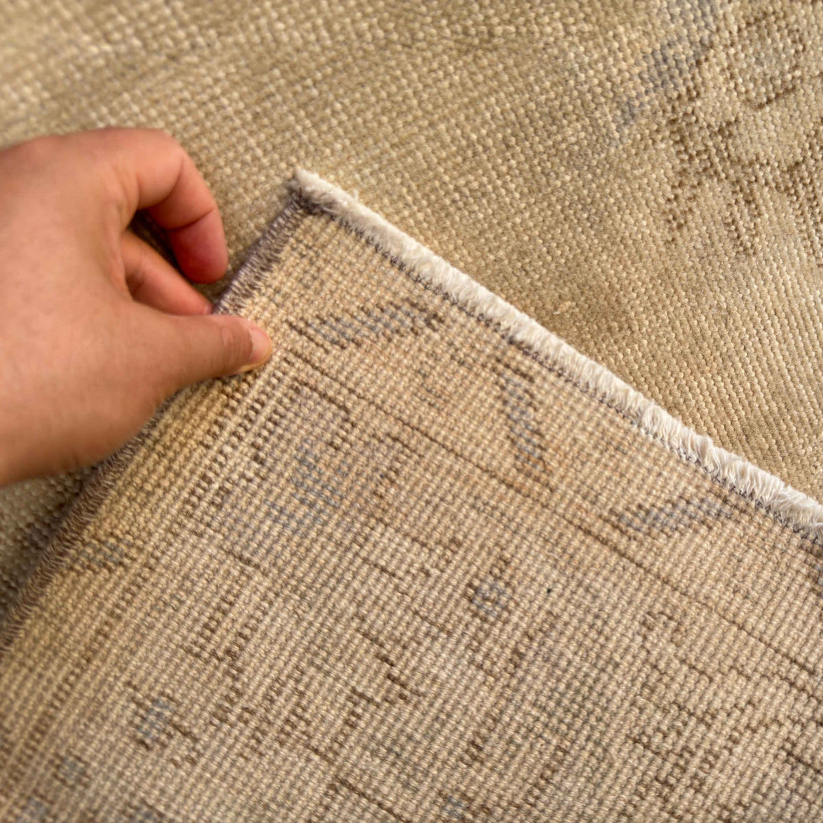 Close-up of the beige vintage turkish rug showing neutral details, hand-knotted weave, wool and cotton and low pile.