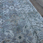 Close-up of the gray vintage turkish rug showing floral details, hand-knotted weave, wool and cotton and low pile.