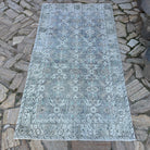 Gray 4' x 7' vintage turkish rug in wool and cotton, shown on the floor.