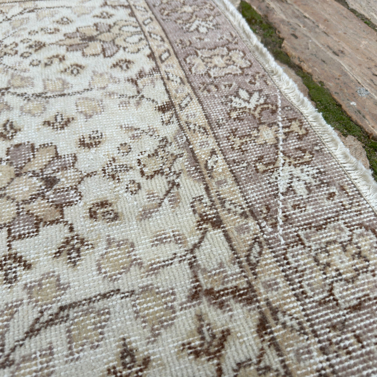 Close-up of the pale pink vintage turkish rug showing floral details, hand-knotted weave, wool and cotton and low pile.