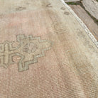 Close-up of the pale pink vintage turkish rug showing medallion details, hand-knotted weave, wool and cotton and low pile.