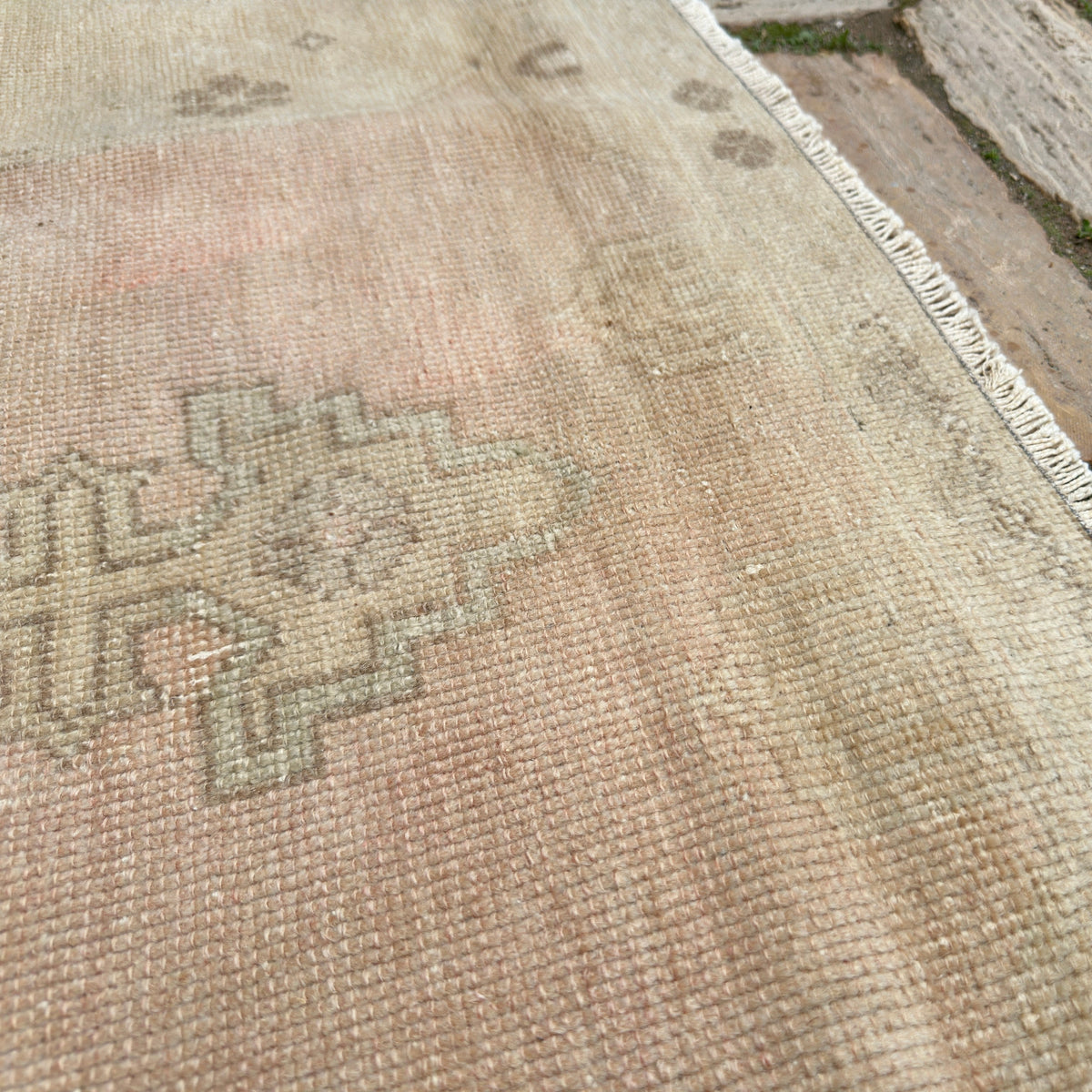 Close-up of the pale pink vintage turkish rug showing medallion details, hand-knotted weave, wool and cotton and low pile.