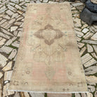 Pale Pink 4' x 7' vintage turkish rug in wool and cotton, shown on the floor.