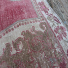 Close-up of the pale red vintage turkish rug showing traditional details, hand-knotted weave, wool and cotton and low pile.