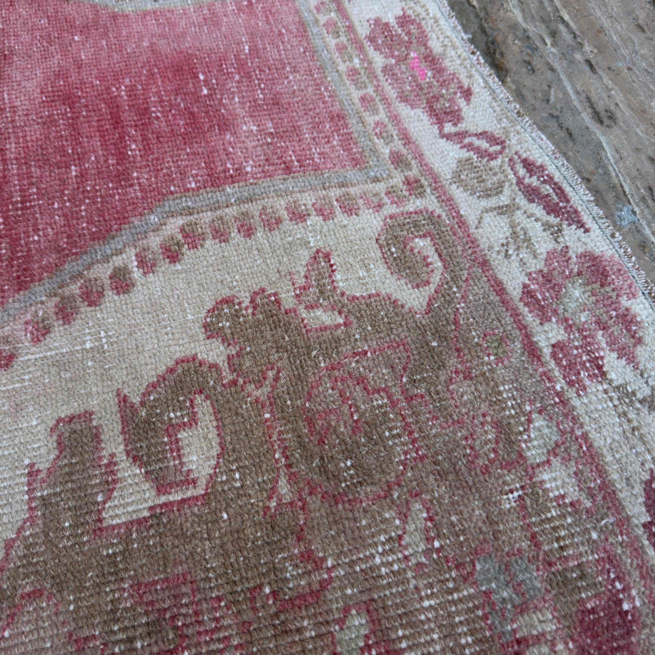 Close-up of the pale red vintage turkish rug showing traditional details, hand-knotted weave, wool and cotton and low pile.