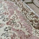 Close-up of the pink vintage turkish rug showing medallion details, hand-knotted weave, wool and cotton and low pile.