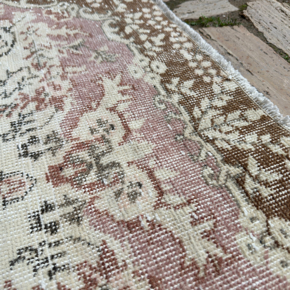 Close-up of the pink vintage turkish rug showing medallion details, hand-knotted weave, wool and cotton and low pile.