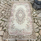 Pink 4' x 7' vintage turkish rug in wool and cotton, shown on the floor.