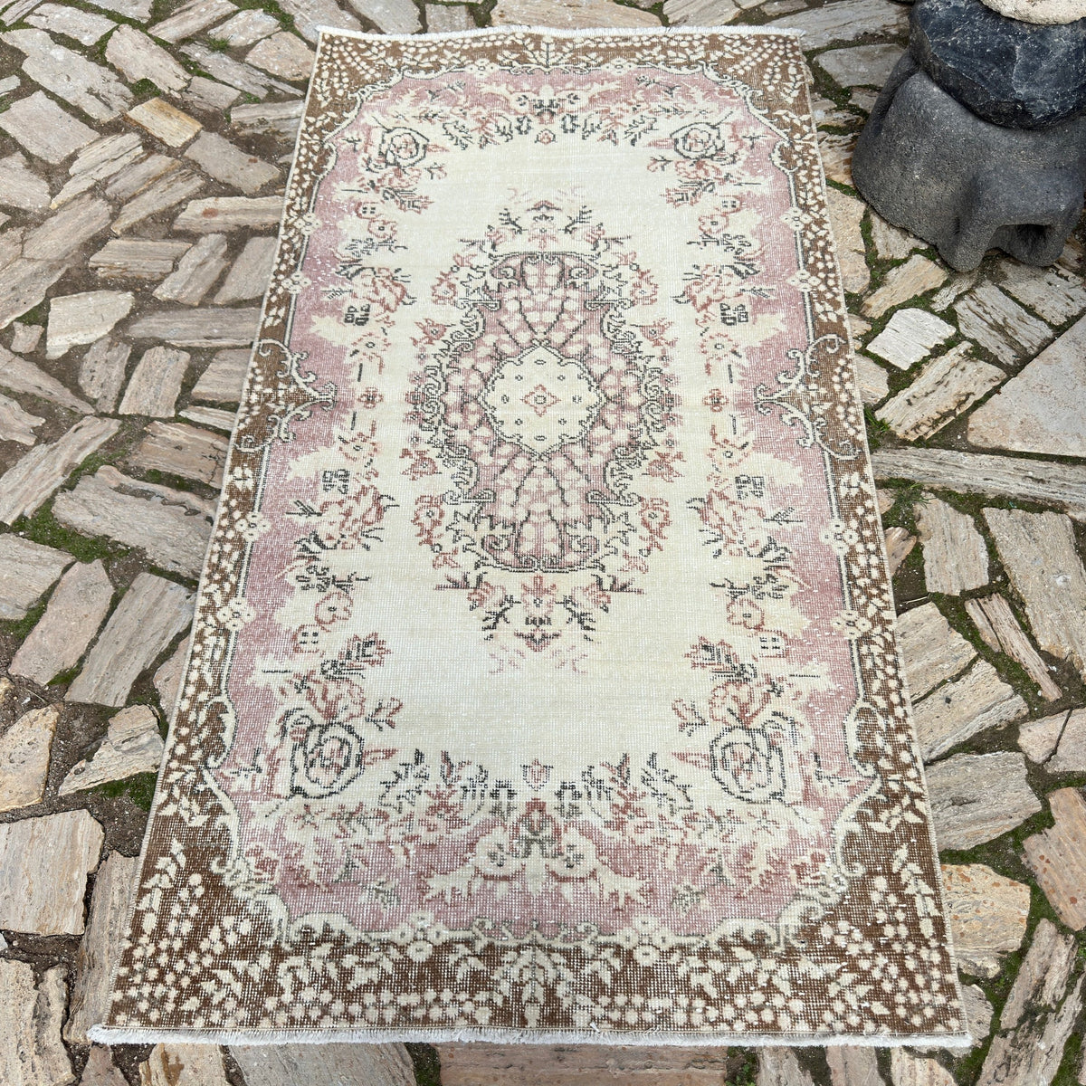Pink 4' x 7' vintage turkish rug in wool and cotton, shown on the floor.